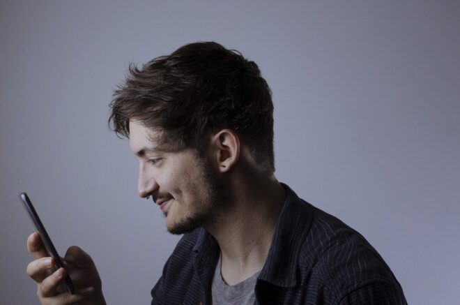 Un homme regarde son smartphone en souriant 